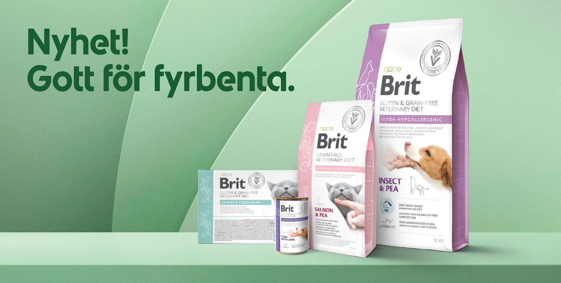 Fyra Brit djurfoderpaket i olika storlekar och färger står på en grön hylla mot en ljusgrön vägg med texten "Nyhet! Gott för fyrbenta".