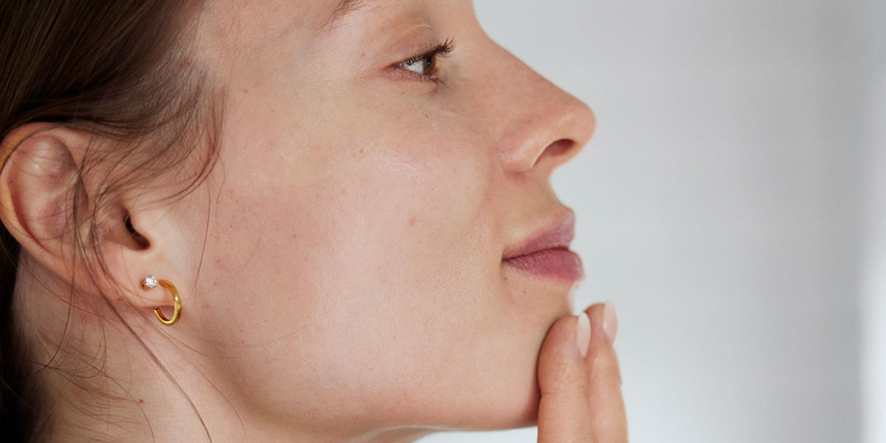 Kvinna som håller i sin hake, kollar bort från kameran. 