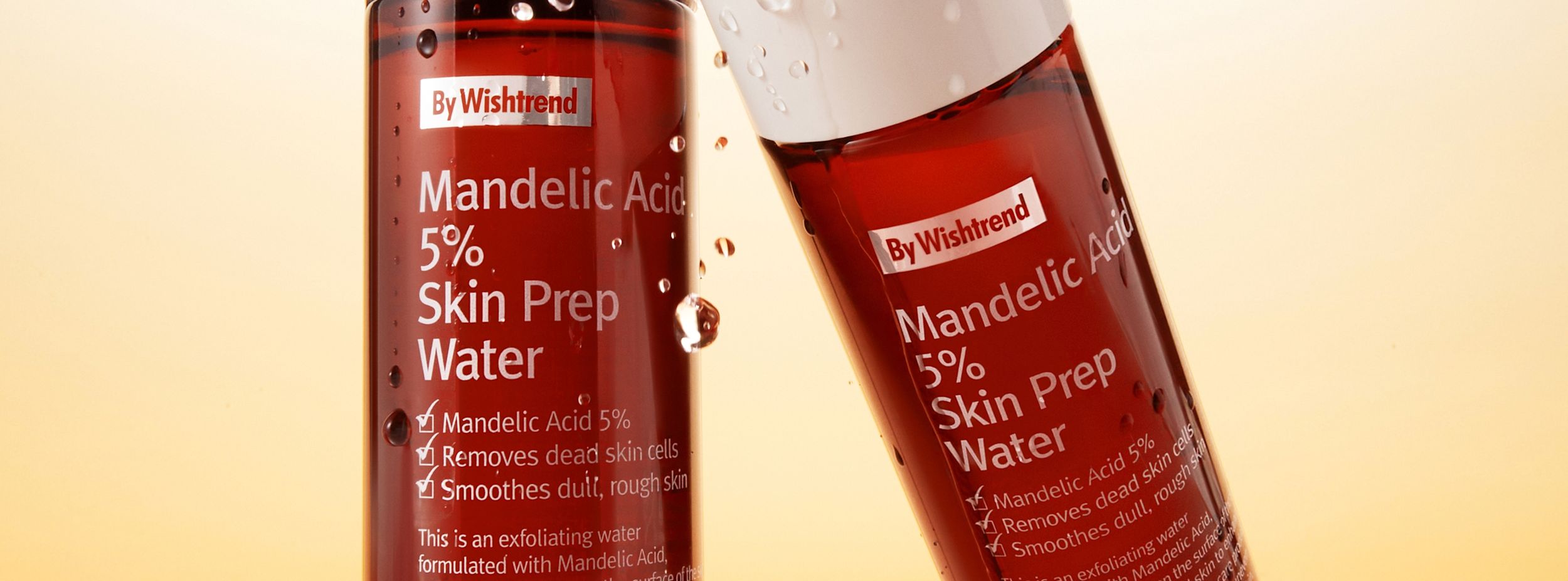Två flaskor By Wishtrend Mandelic Acid 5% Skin Prep Water med vattendroppar mot en ljus bakgrund.