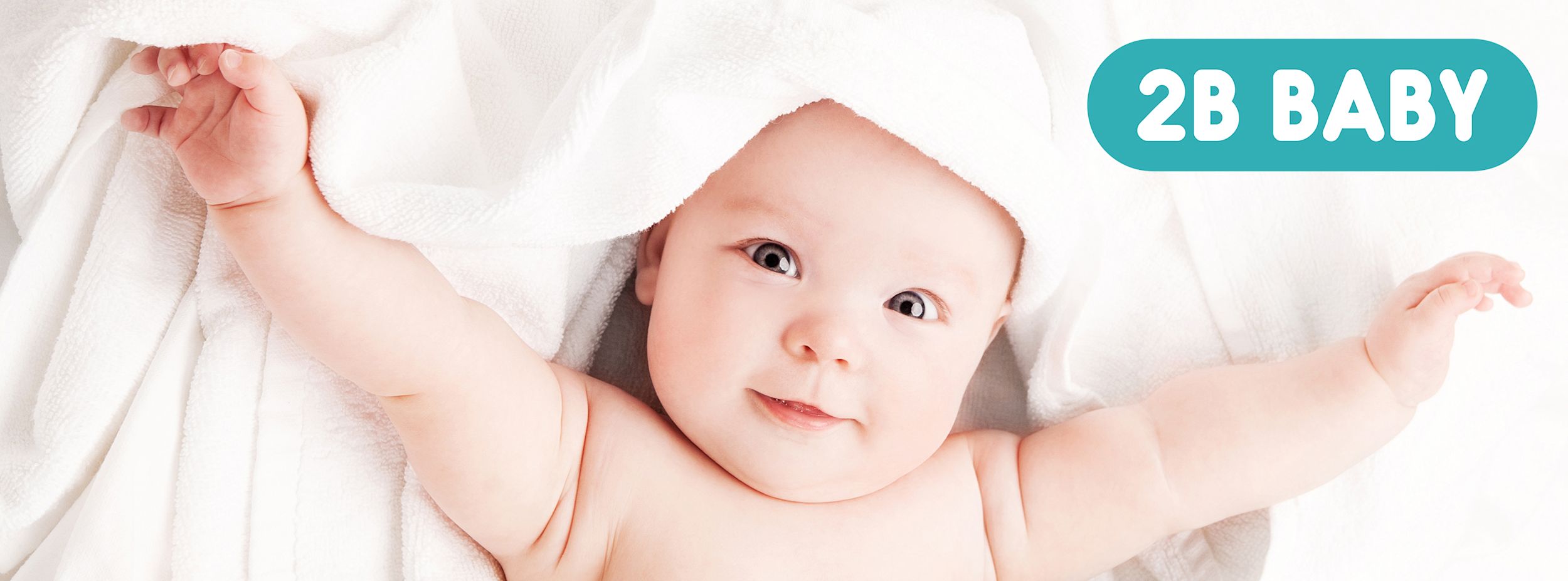 Bebis ligger på en vit handduk med armarna utsträckta och texten "2B BABY" i blå ruta ovanför.