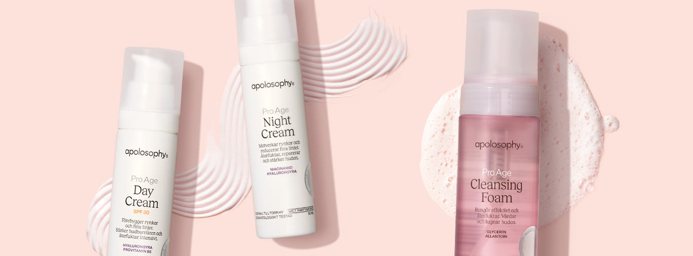 Tre Apolosophy Pro Age hudvårdsprodukter: Day Cream, Night Cream och Cleansing Foam, placerade mot en ljusrosa bakgrund.