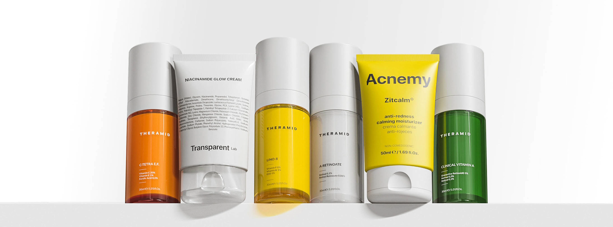 Sex olika hudvårdsprodukter från Theramid och Acnemy står uppradade på en vit yta, med färgglada förpackningar i orange, vit, gul och grön.