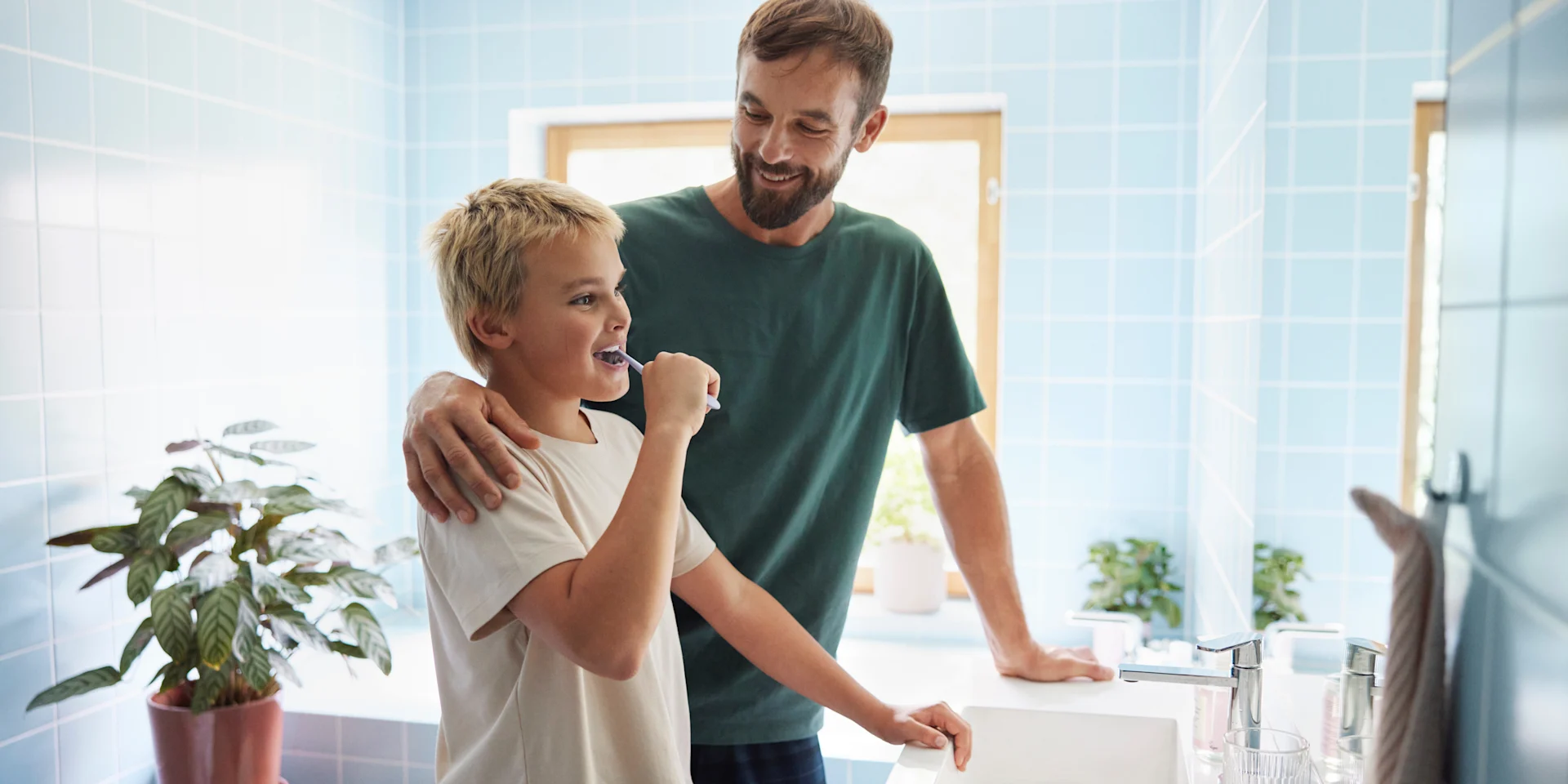 Pappa och son står i badrummet, pappa har armen om sonens axlar medan sonen borstar tänderna.