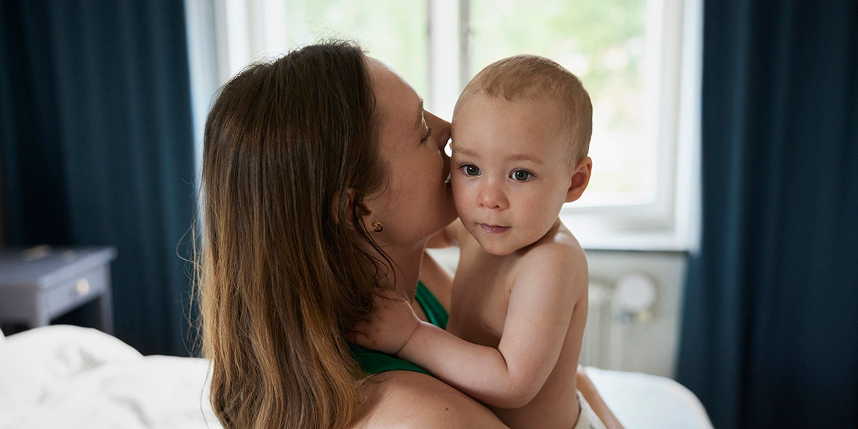 Mamma håller i barn i ett sovrum.