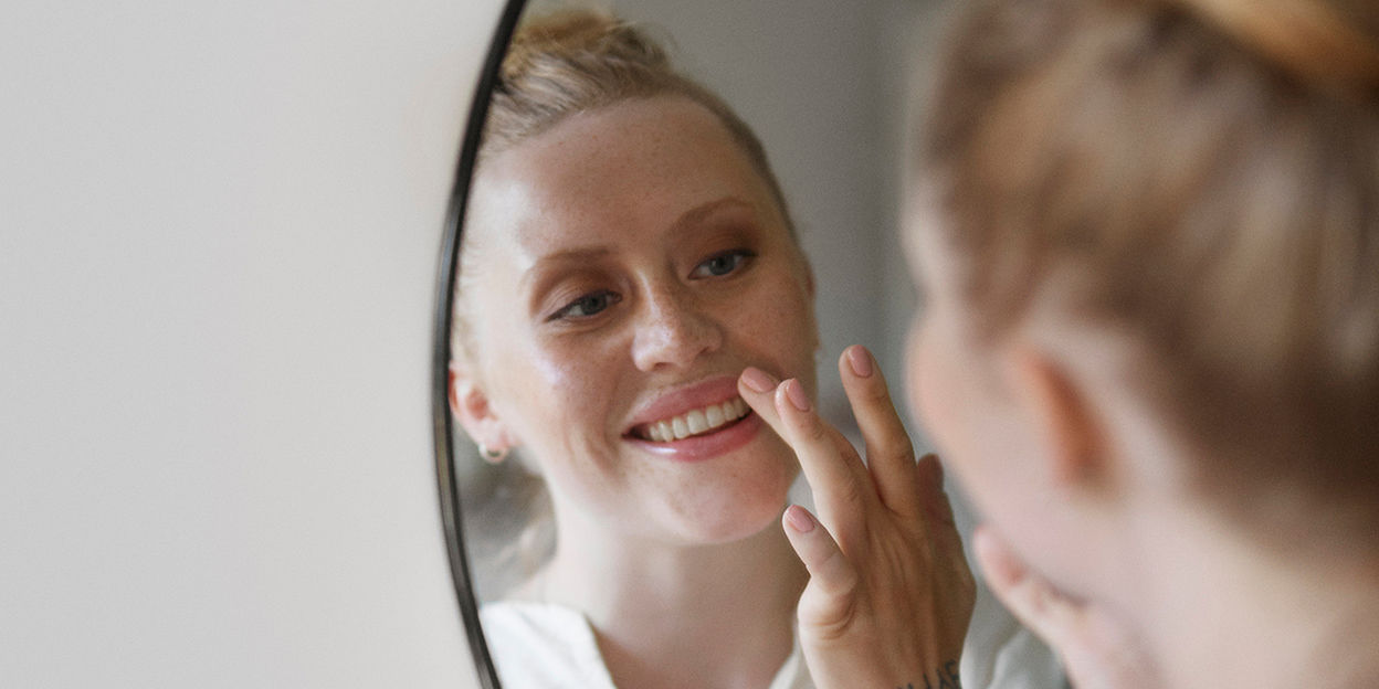 Kvinna speglar sig och ler.