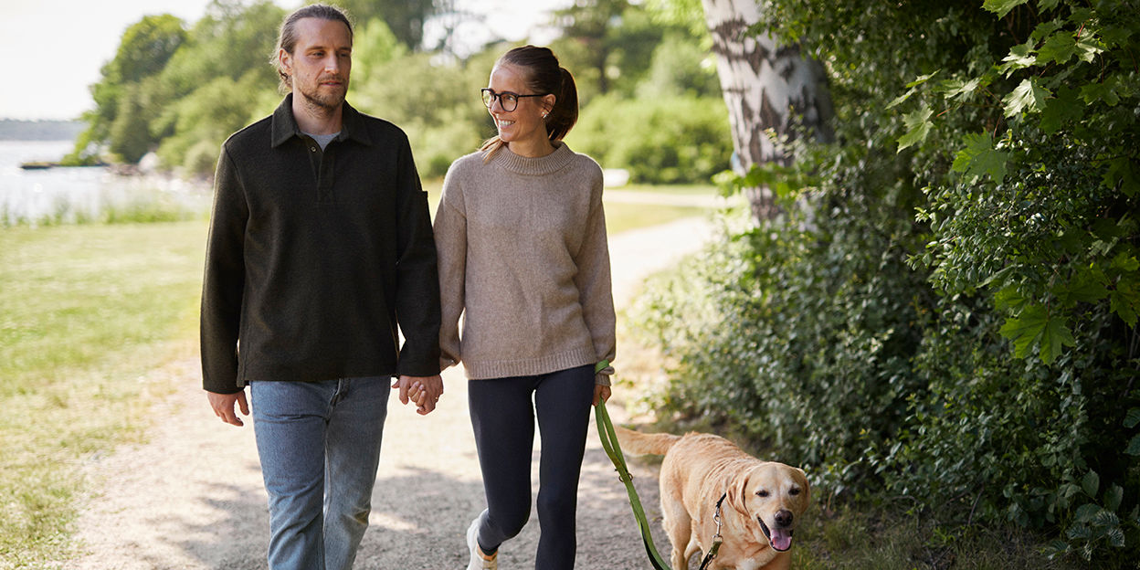 Man och kvinna är ute och promenerar i naturen och håller hand.
