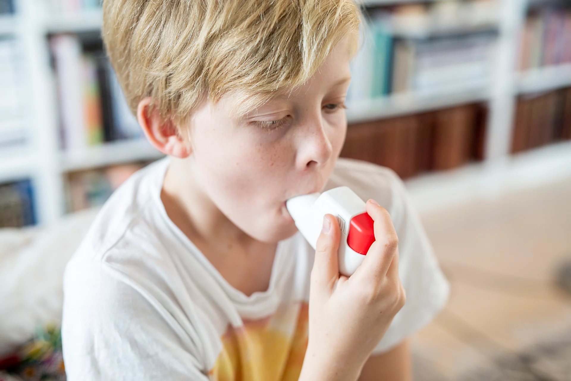 En ung pojke använder en inhalator för astma.