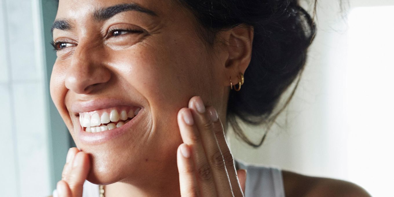 Kvinna smörjer in ansiktet och skrattar.