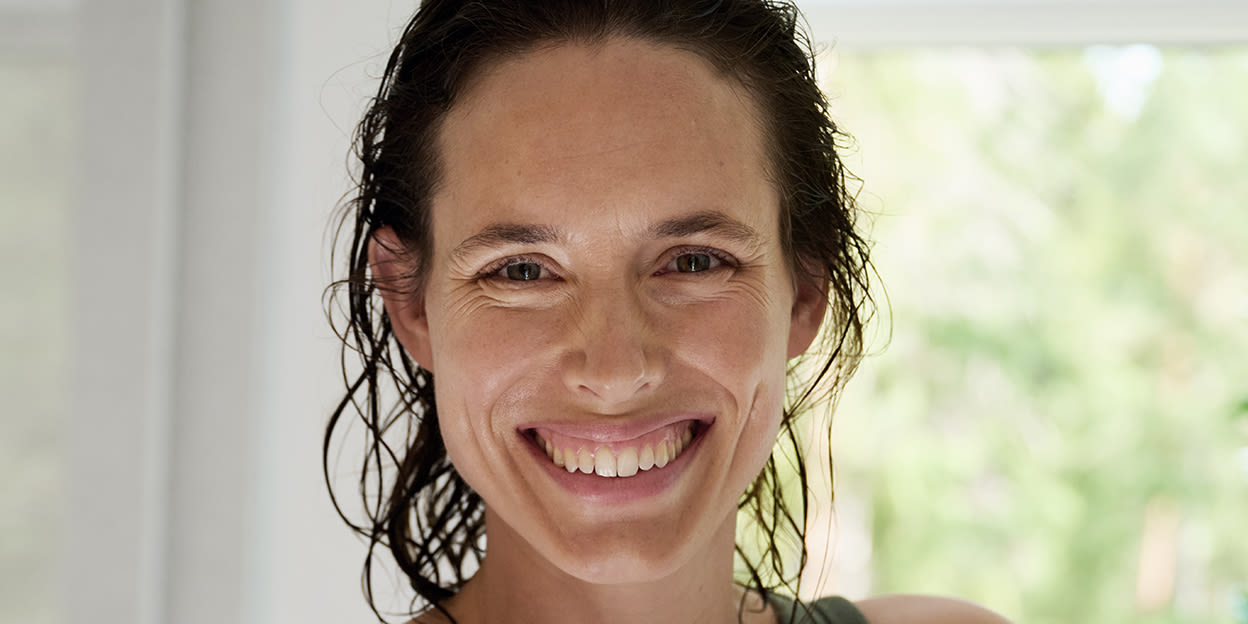 Glad nyduschad kvinna med blött hår i badrumsmiljö.