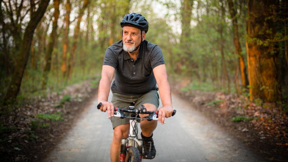 Man med cykelhjälm cyklar genom skogen.