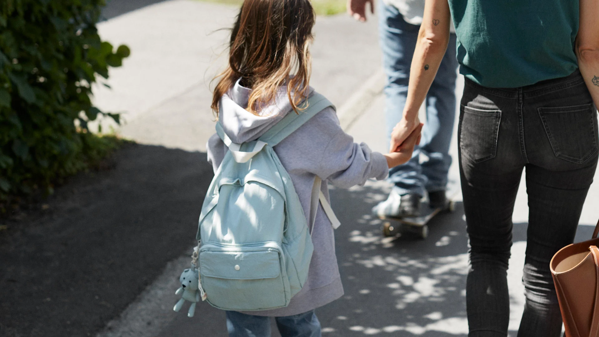 En flicka som går och håller hand med sin mamma, på väg till skolan.