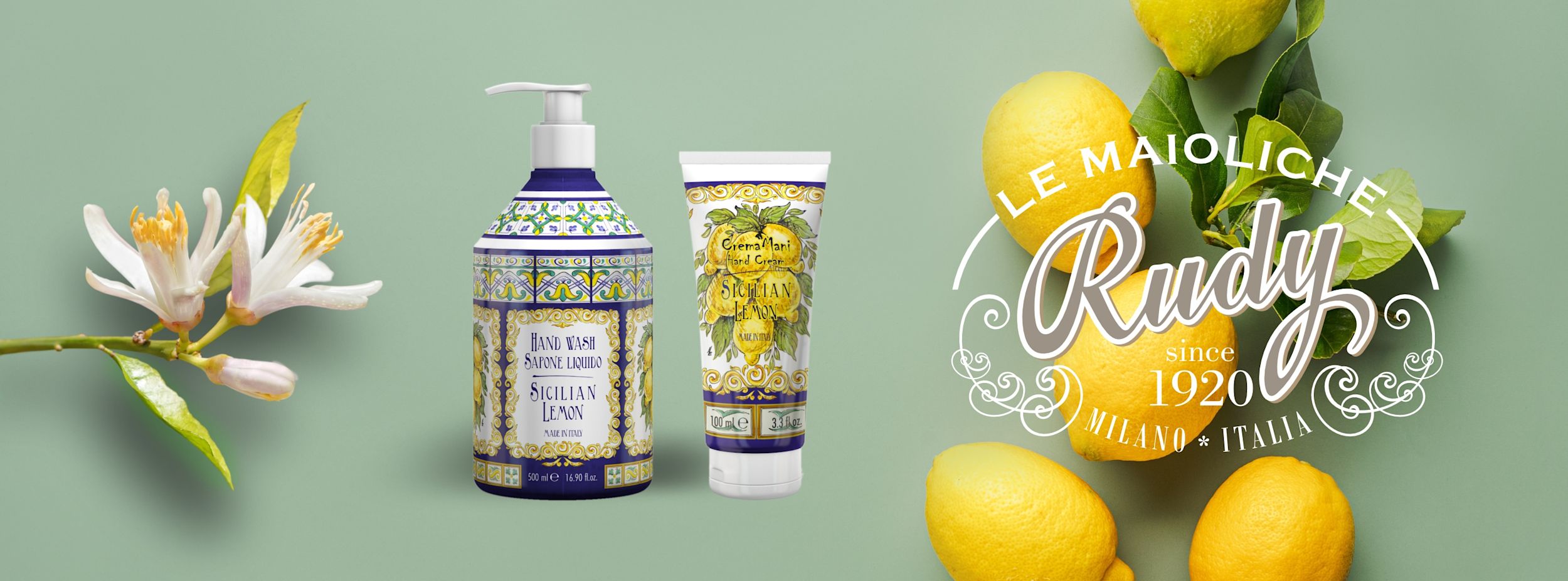 Två produkter med siciliansk citron, handtvål och handkräm, står bredvid citronblommor och färska citroner på grön bakgrund.